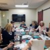 Corporate team engaged in vision board building and goal settining seated around conference table.