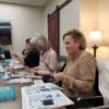 Female business owners sitting around table goal setting and building dream boards